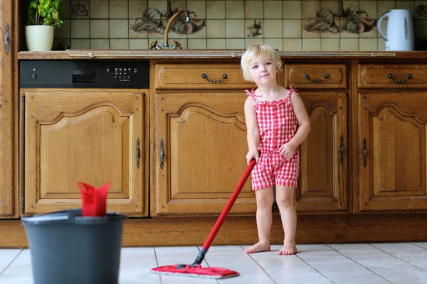 Lovely preschooler girl mopping the floor in kitchen — Stock Photo, Image