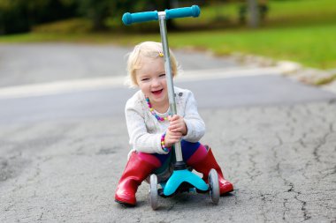 Küçük kız sokakta itme scooter üzerinde sürme