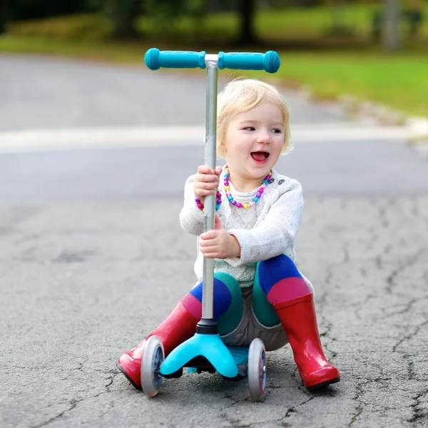 Маленькая девочка катается на скутере по улице — стоковое фото