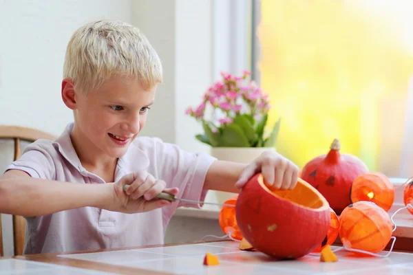 Happy boy carving pumpkin for halloween — Stock Photo, Image