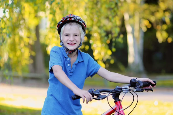 Happy school boy ridning cykel i park — Stockfoto