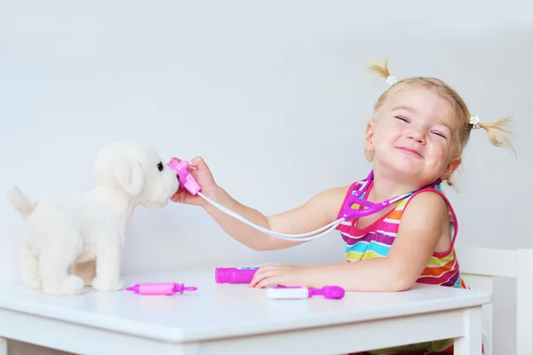 Doktor oyuncak köpek yavrusu ile oynayan küçük kız — Stok fotoğraf