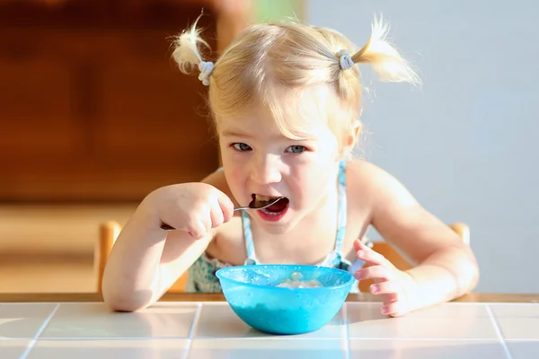 Toddler girl eating oatmeal for breakfast Stock Picture