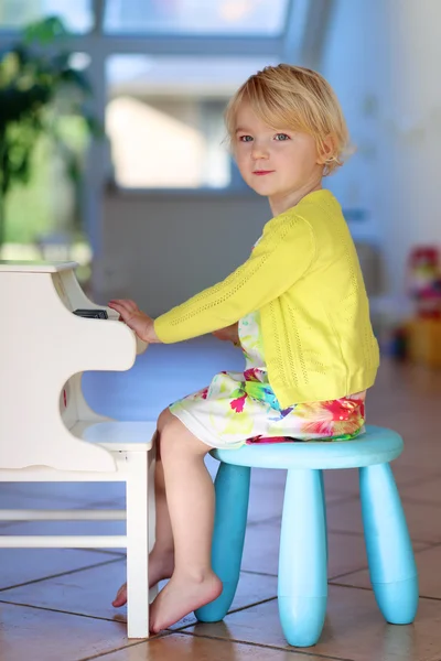Bambina che gioca a pianoforte giocattolo a casa — Foto Stock
