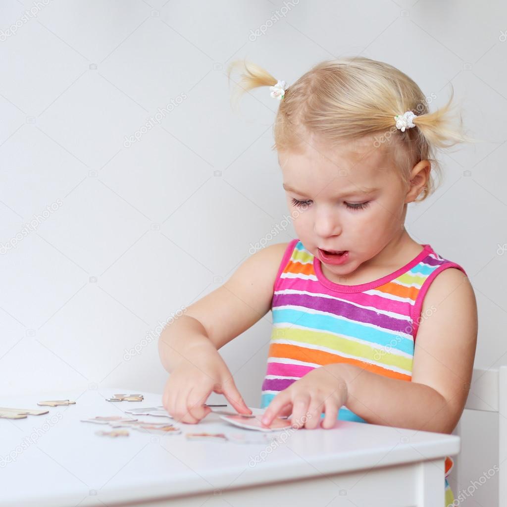 Toddler girl assembling jigsaw puzzle