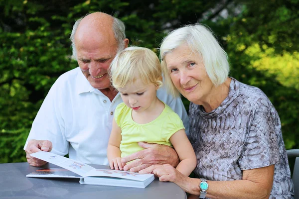 Grootouders met kleinkind op zoek familie fotoalbum — Stockfoto