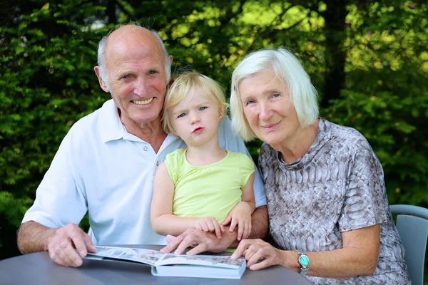 Großeltern mit Enkelkind suchen Familienfotoalbum — Stockfoto
