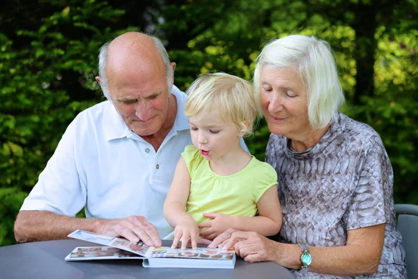 Abuelos con nieto buscando álbum de fotos familiares — Foto de Stock