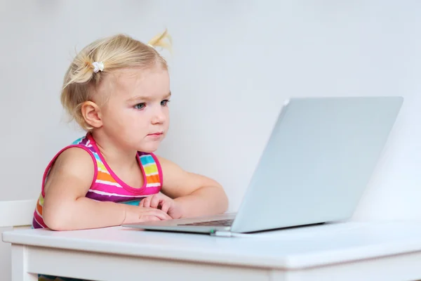 小さな女の子がラップトップで遊んで — ストック写真