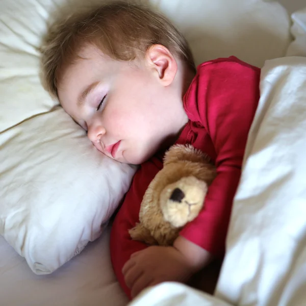 Toddler girl sleeping in bed with teddy bear — Stock Photo, Image
