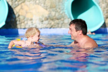 Baba ve kızı havuzda yüzüyor.