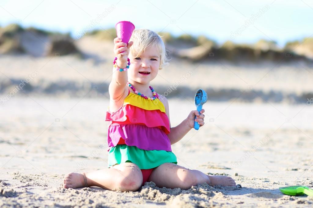Happy little girl playing on the beach