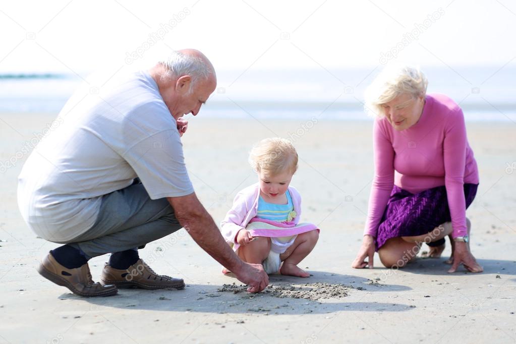 Grandparents with granddaughter playing on the beach