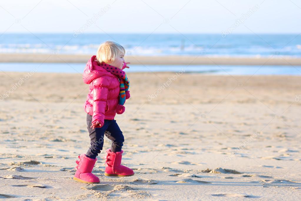 Little girl playing on the beach at winter