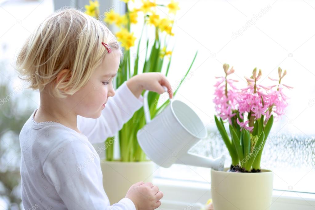 Little girl watering spring flowers