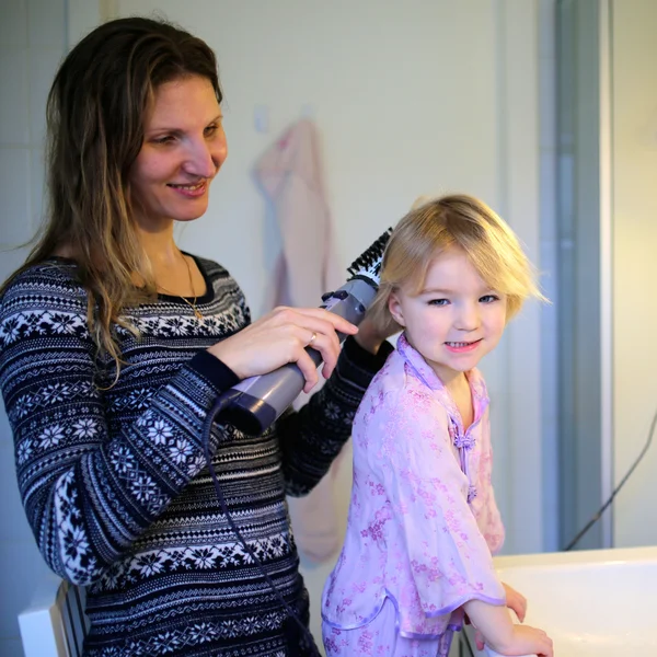 Madre e hija pequeña cepillando el cabello usando estilista —  Fotos de Stock