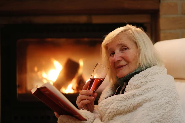 Senior dame ontspannen thuis bij open haard — Stockfoto