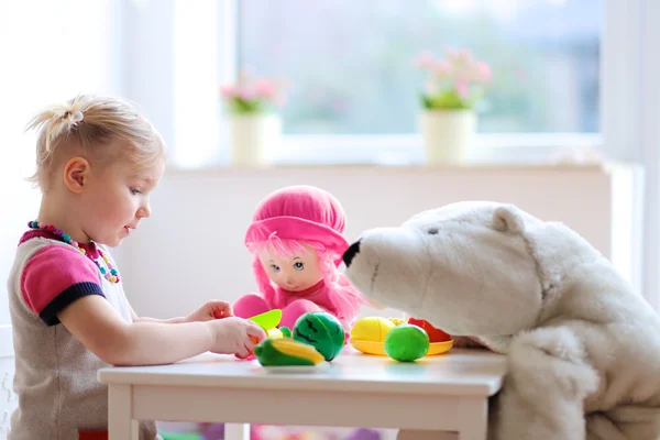 Menina pré-escolar brincando com brinquedos de plástico legumes — Fotografia de Stock