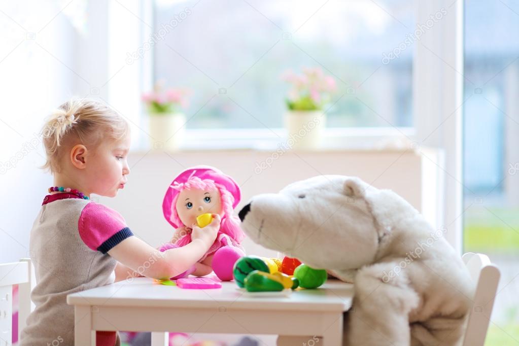 Preschooler girl playing with plastic toys vegetables