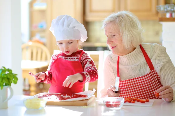 Oma mit Enkelin bereitet Pizza zu — Stockfoto