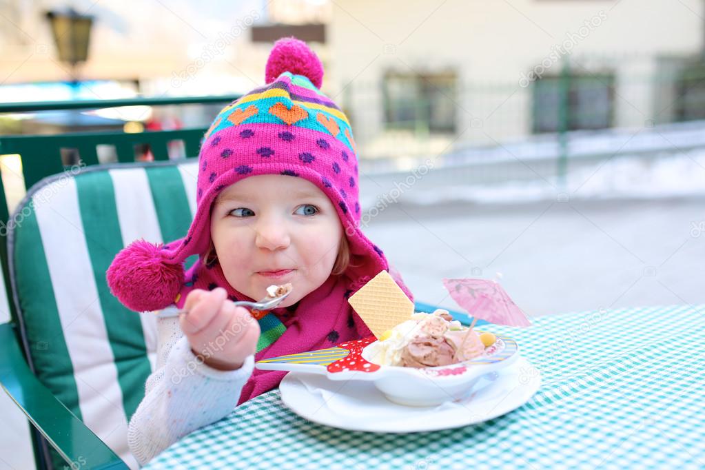 Little girl eating ice cream in cafe
