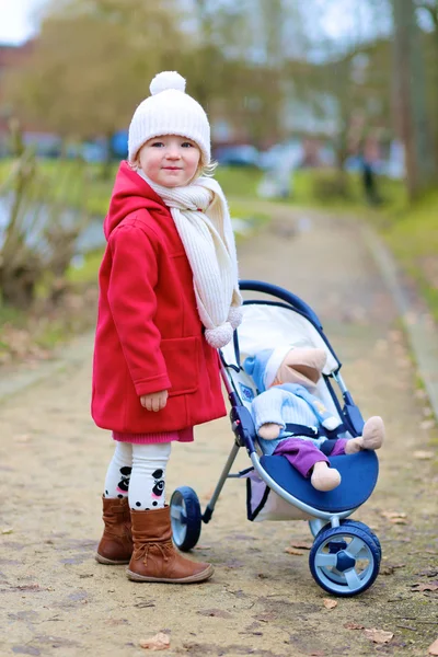 Kleines Mädchen läuft mit Kinderwagen im Park — Stockfoto