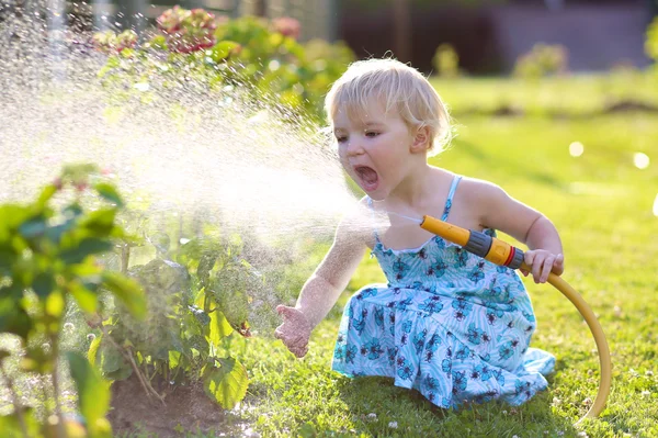 Niedliches kleines Mädchen beim Blumengießen im Garten — Stockfoto