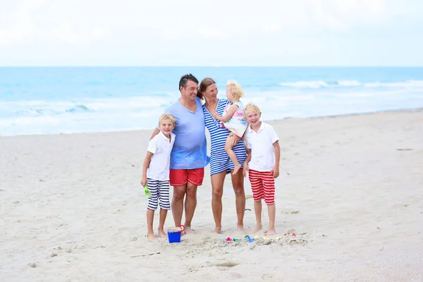 Lycklig familj njuter av sommarlovet på stranden — Stockfoto