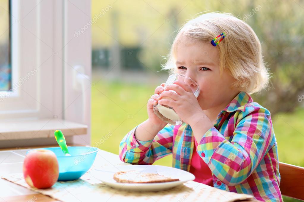 Little girl having toast and milk for breakfast