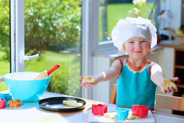 Happy toddler girl preparing cookies