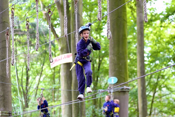 Chico de escuela feliz escalando en parque de aventura — Foto de Stock