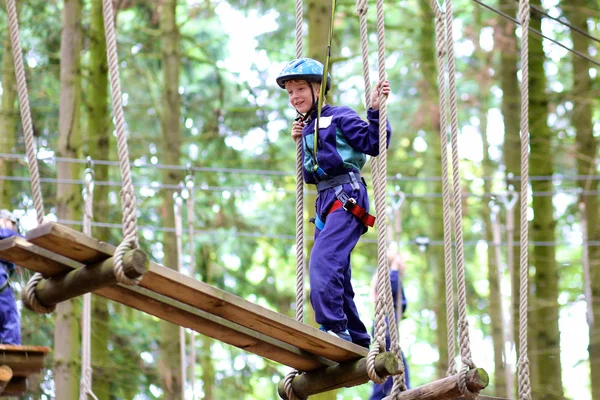 Happy school boy climbing in adventure park — Stock Photo, Image