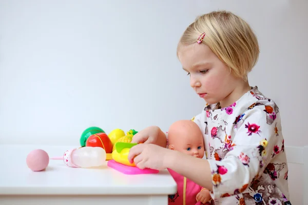 Маленькая девочка играет с куклами в помещении — стоковое фото