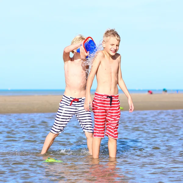 Två aktiva pojkar spelar på stranden — Stockfoto