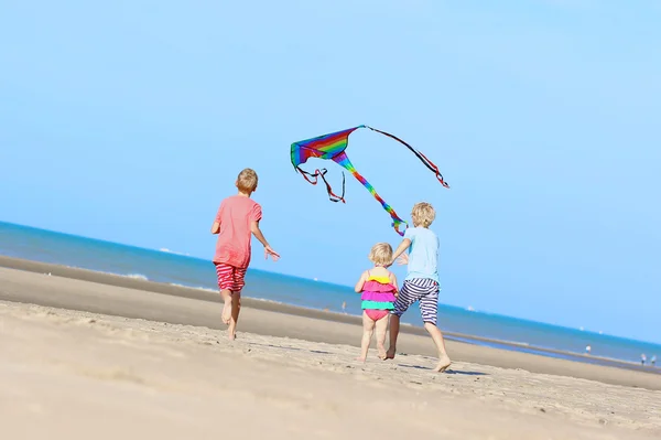 Crianças felizes brincando com pipa na praia — Fotografia de Stock