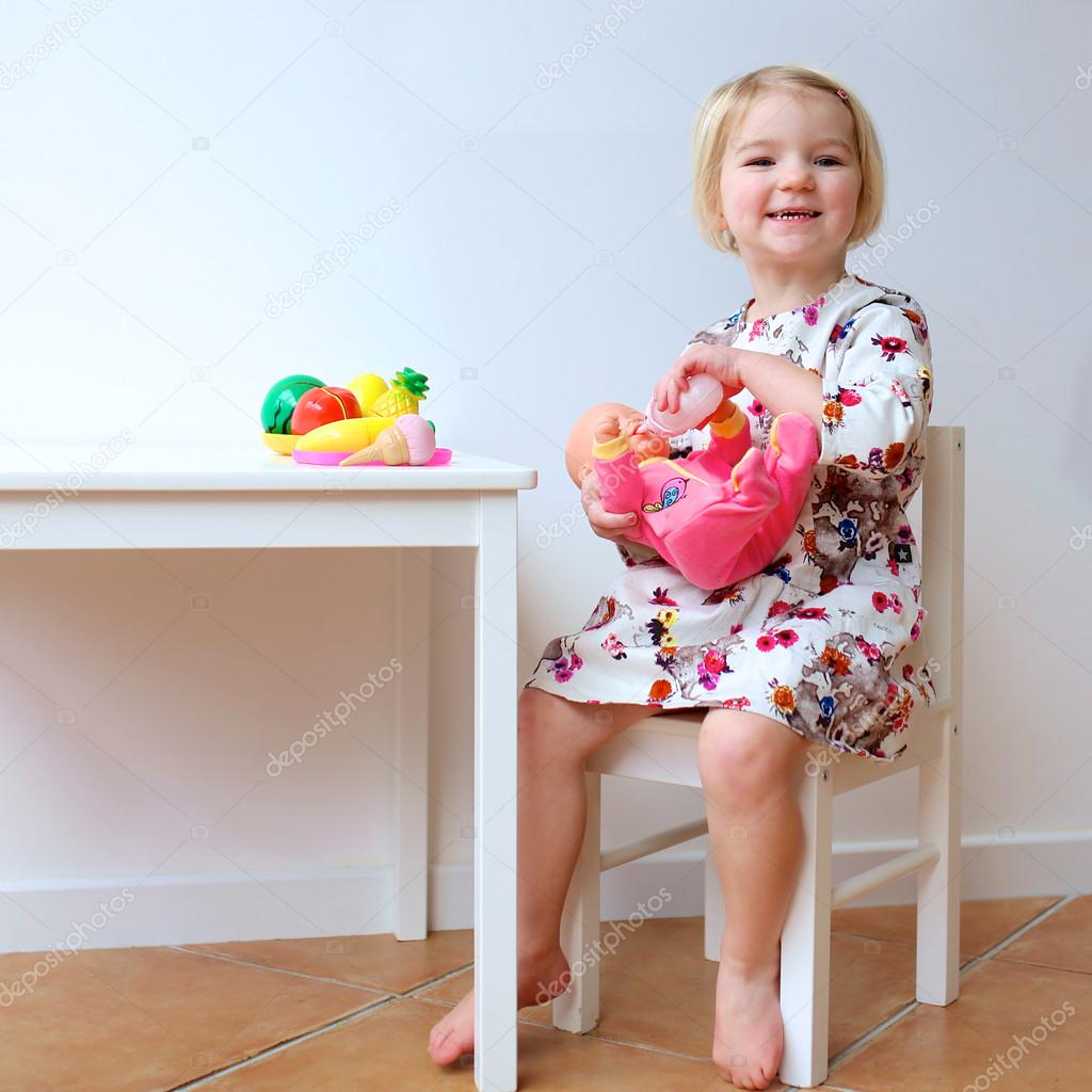 Toddler girl playing with dolls indoors