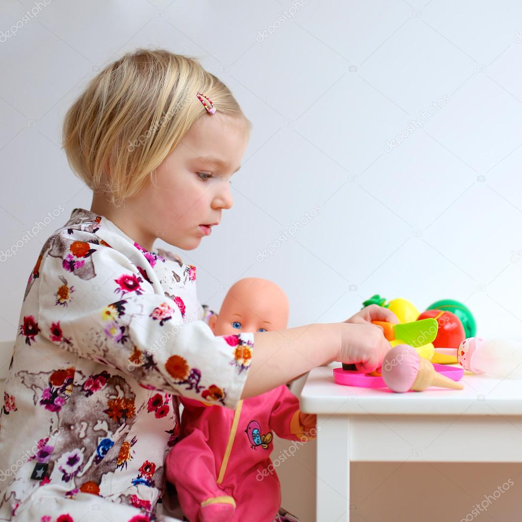 Toddler girl playing with dolls indoors