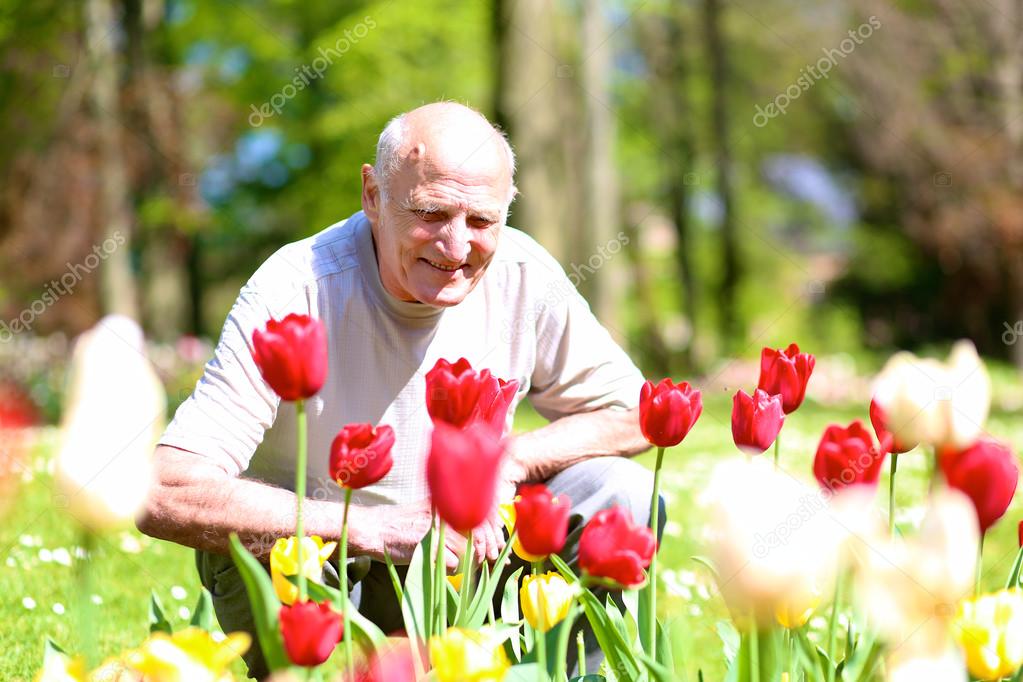 Happy senior man enjoying flowers park