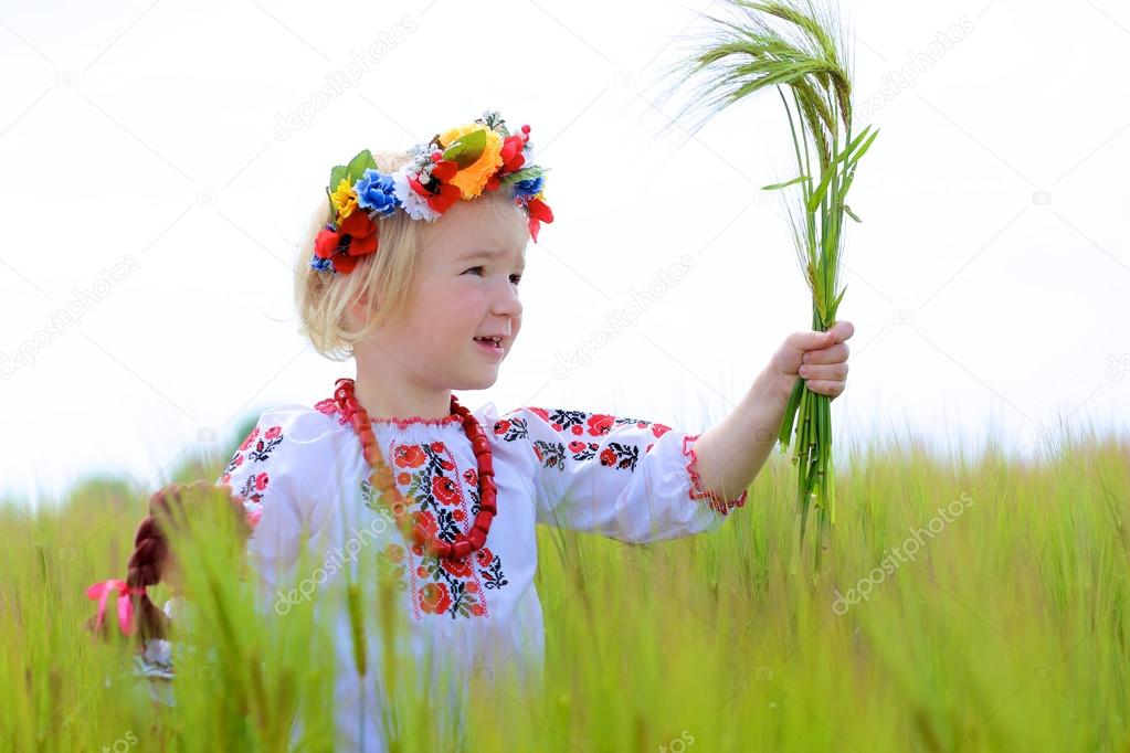 Little girl in Ukrainian dress playing in the field