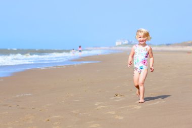 Little girl playing on the beach at summer