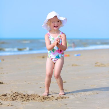 Little girl playing on the beach at summer