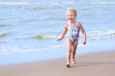 Little girl playing on the beach at summer