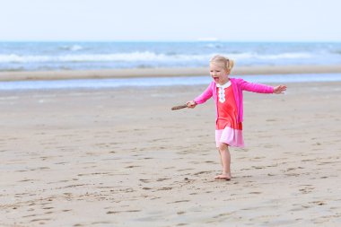 Little girl playing on the beach at summer