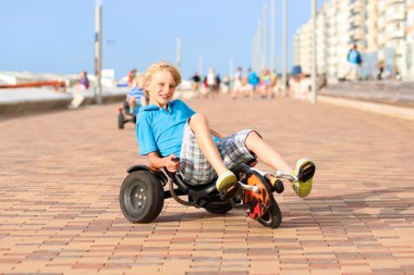 Happy boy riding pedal car on the beach
