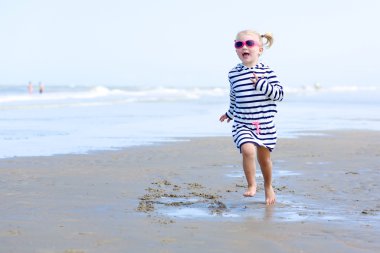 Little girl playing on the beach at summer