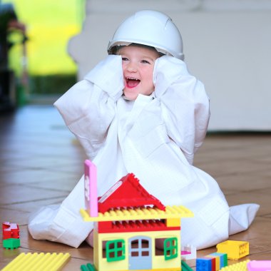 Toddler girl wearing safety helmet playing with building blocks