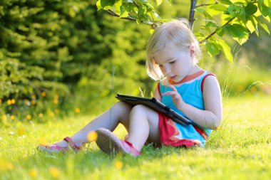 Toddler girl using tablet pc outdoors