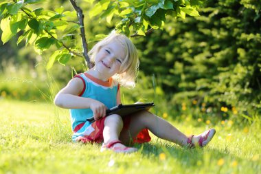 Toddler girl using tablet pc outdoors