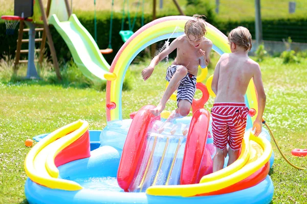 Barnen njuter av uppblåsbara poolen sommardag — Stockfoto