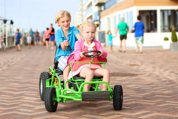 Glückliche Kinder fahren Tretauto am Strand — Stockfoto